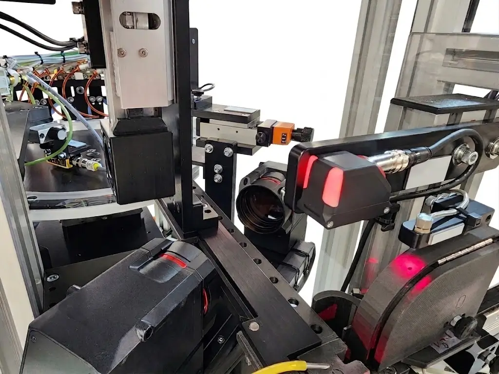 Close-up of machine vision hardware with cameras, lights, and mounting brackets inside an industrial automation frame.